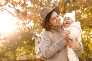 Photo of Happy mother with her baby daughter outdoors on autumn day, space for text