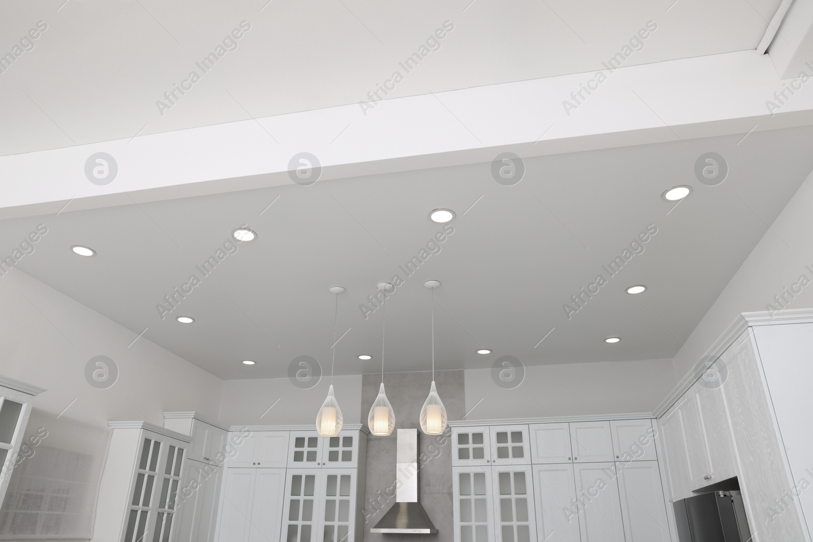 Photo of Ceiling with modern lamps, furniture and cooker hood in stylish kitchen, low angle view