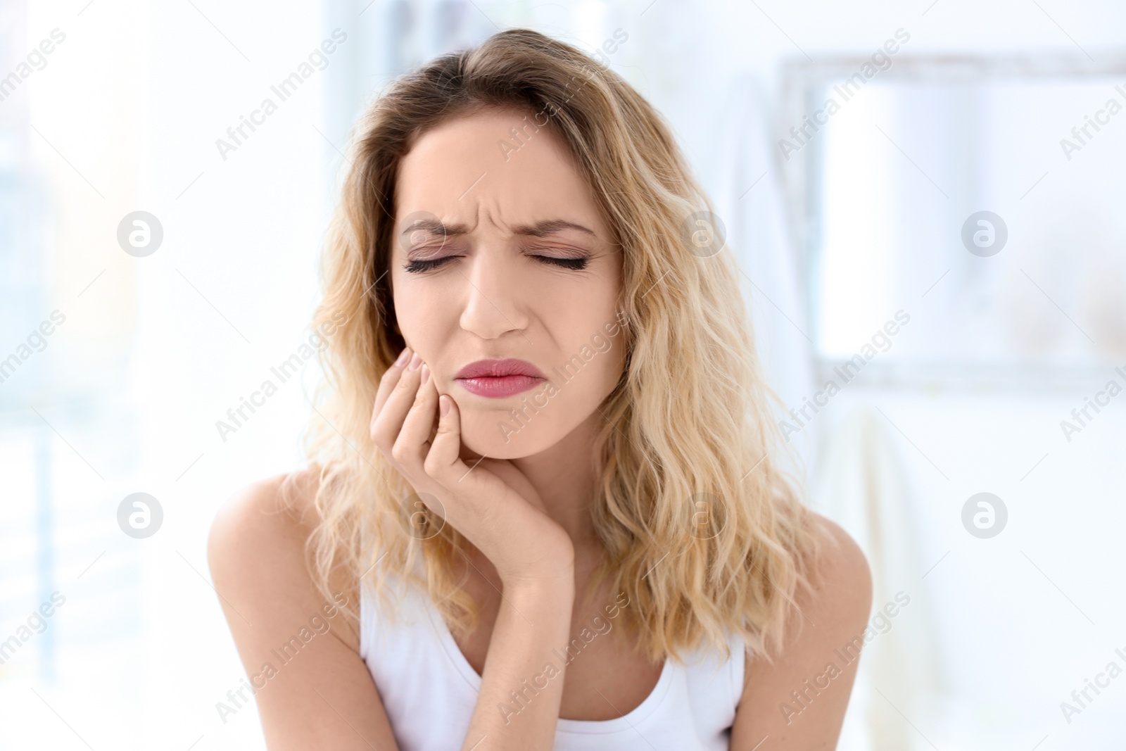 Photo of Young woman suffering from toothache indoors