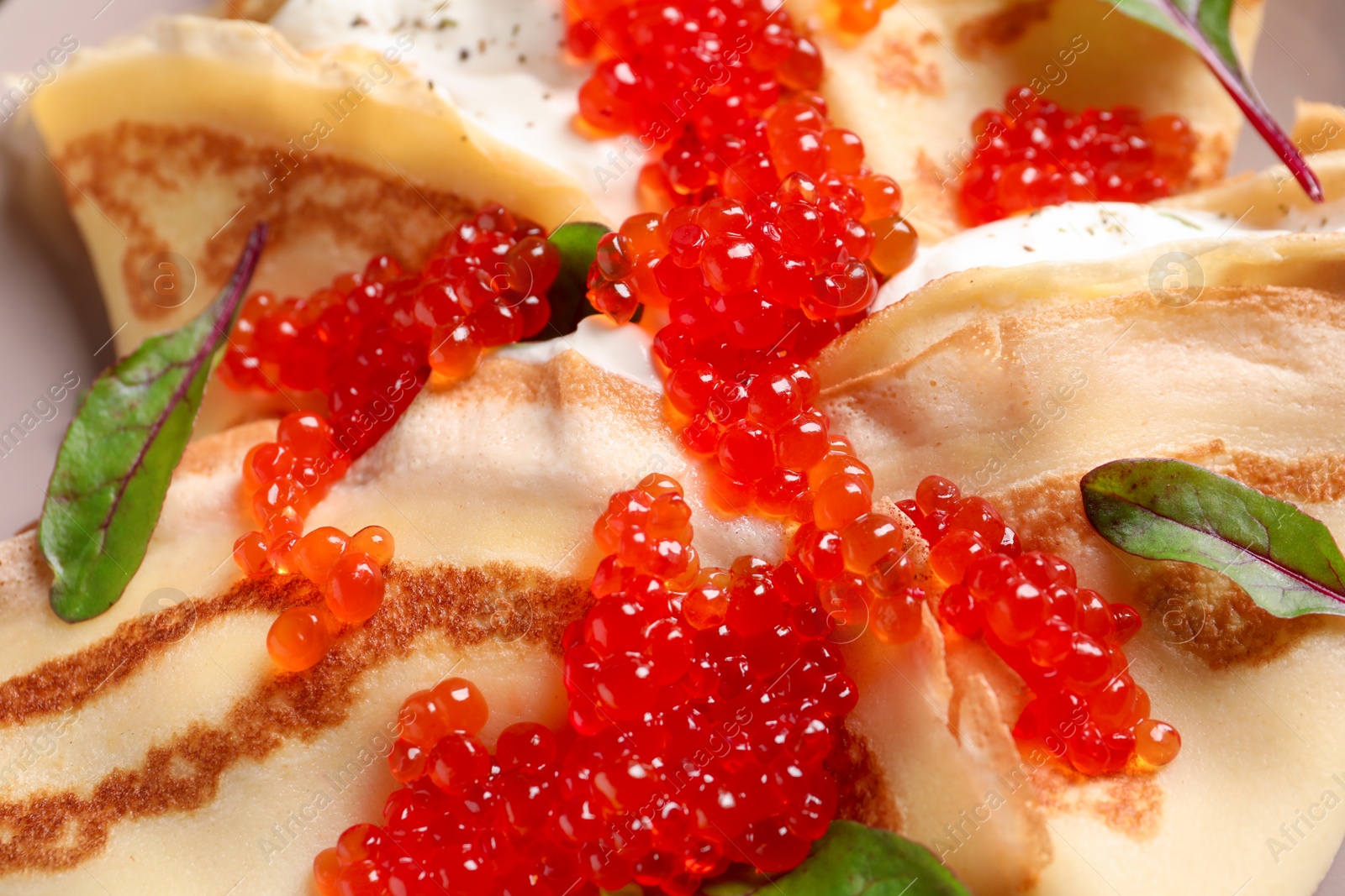 Photo of Thin pancakes with red caviar, closeup