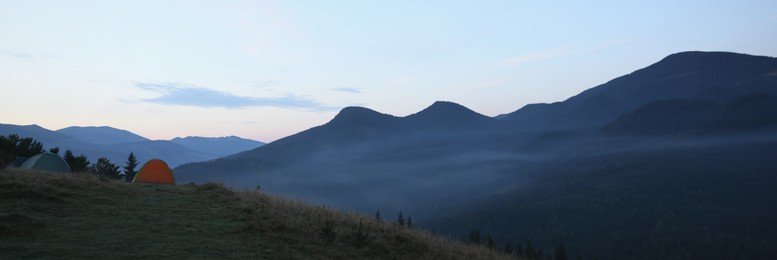 Camping tents on mountain slope in morning, banner design