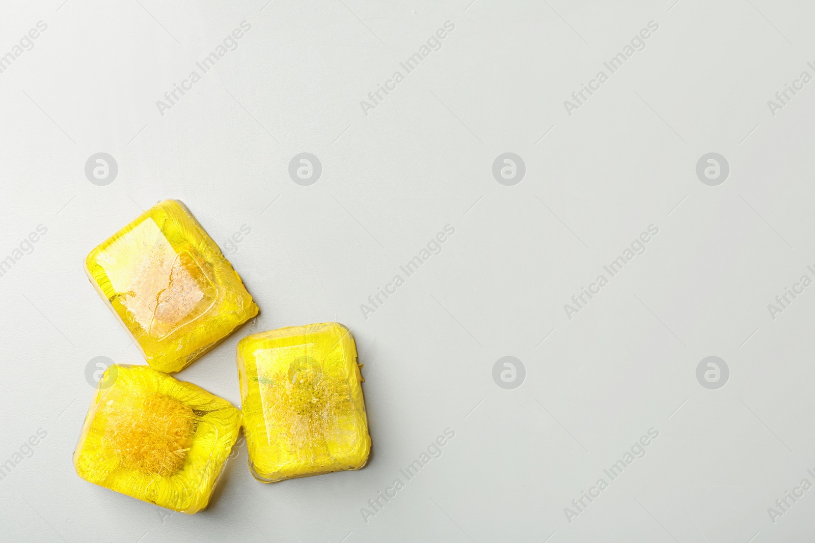 Photo of Ice cubes with flowers on light background, flat lay. Space for text
