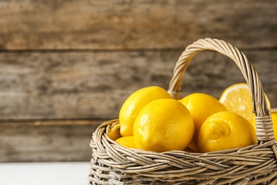 Photo of Basket with ripe lemons against wooden background