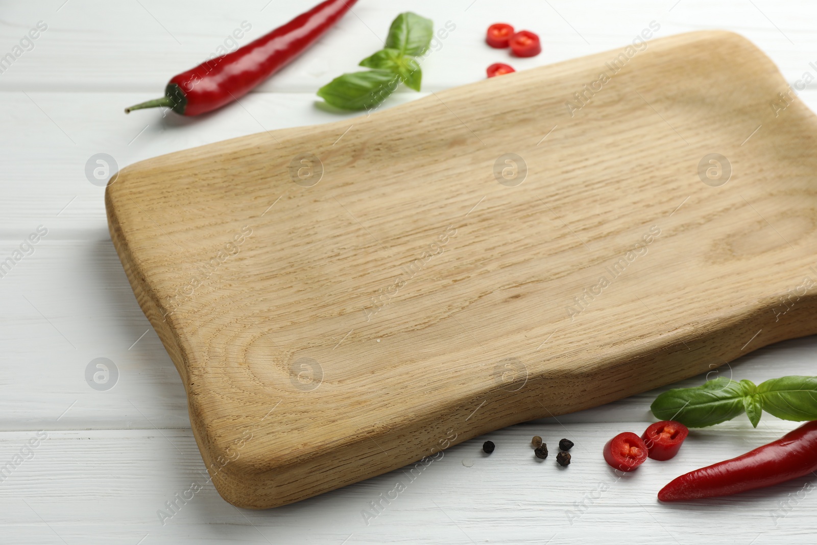 Photo of Cutting board and different spices on white wooden table