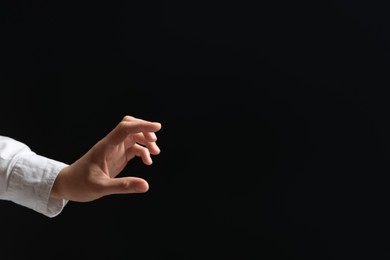 Photo of Woman holding something in hand on black background, closeup. Space for text