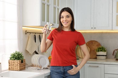 Young woman with glass of water in kitchen