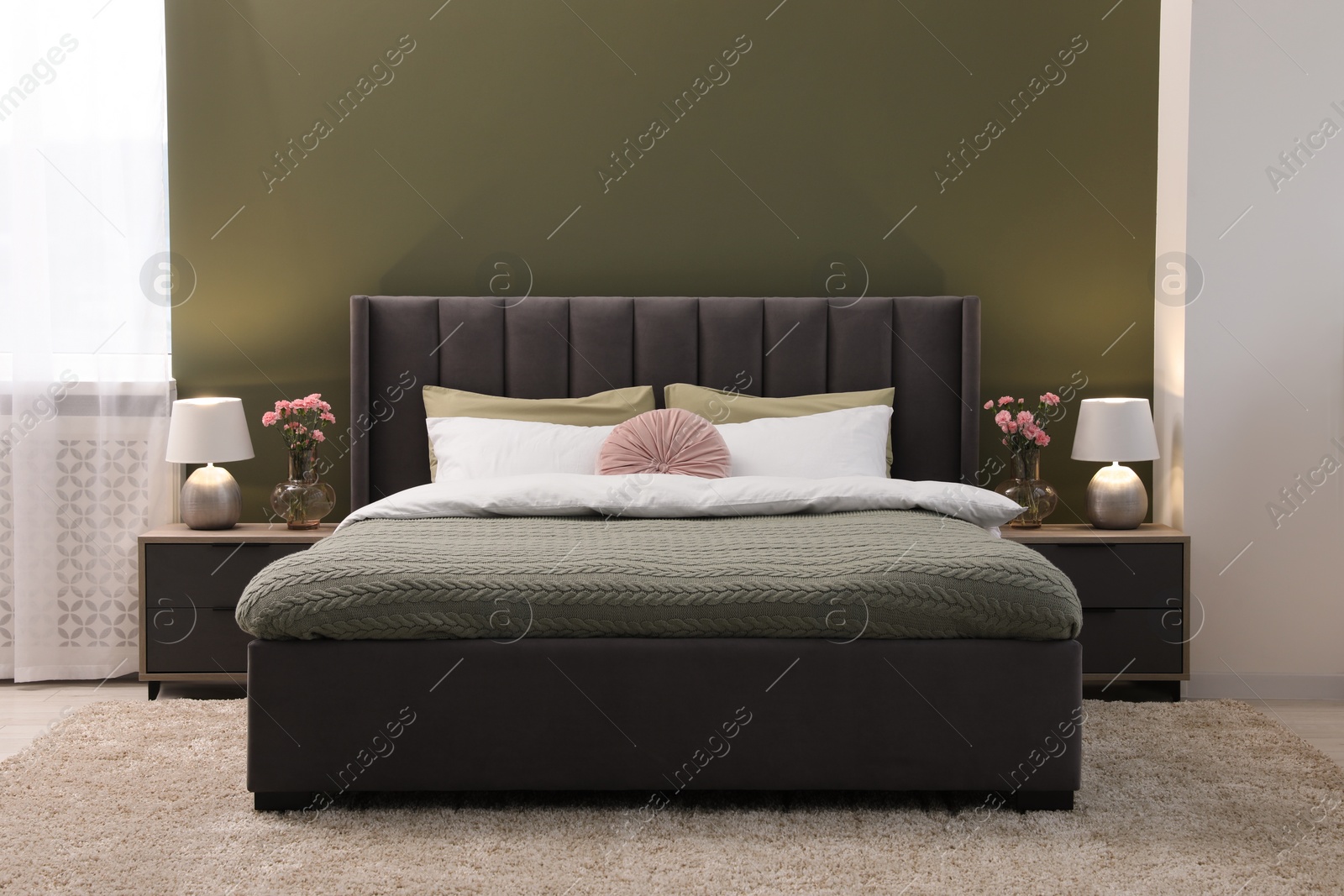 Photo of Large comfortable bed, lamps and beautiful flowers in stylish room. Interior design