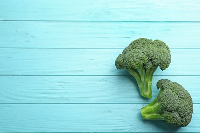 Photo of Flat lay composition of fresh green broccoli on blue wooden table, space for text