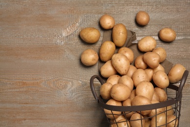 Photo of Raw fresh organic potatoes on wooden background, top view. Space for text