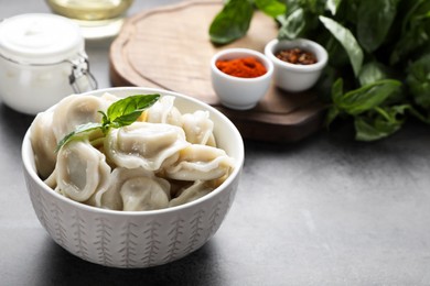 Photo of Tasty dumplings in bowl served on grey table. Space for text