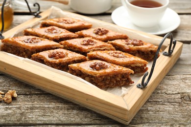 Photo of Delicious sweet baklava with walnuts on wooden table, closeup