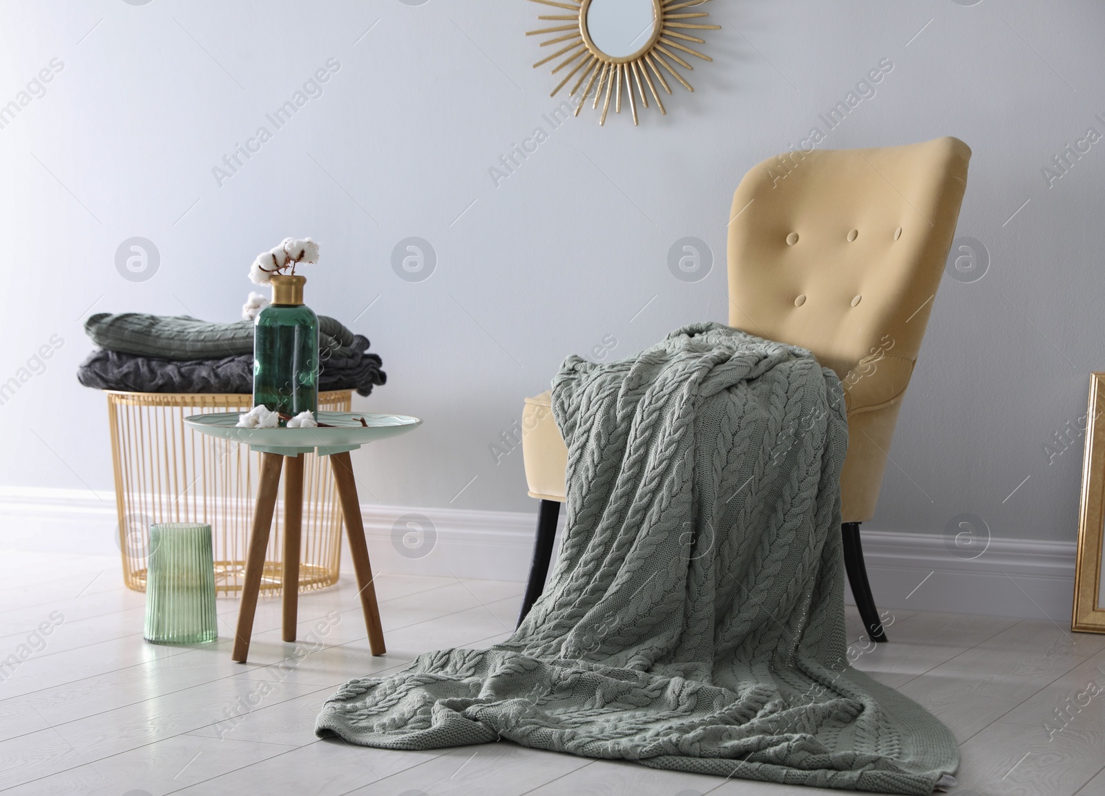 Photo of Soft knitted blanket on armchair in room. Home interior