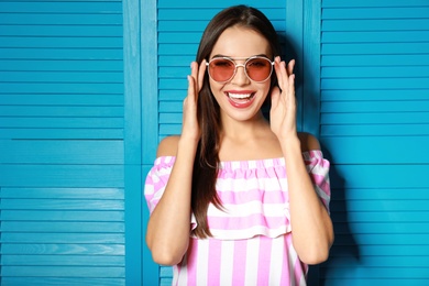 Photo of Beautiful woman in red sunglasses near blue wooden folding screen
