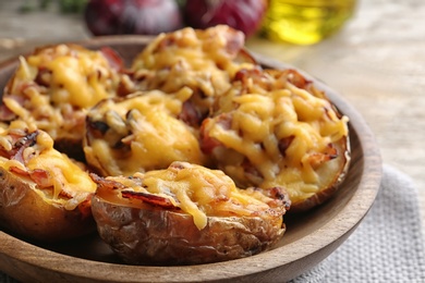 Bowl of baked potatoes with cheese and bacon on table, closeup