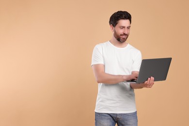 Happy man with laptop on beige background. Space for text