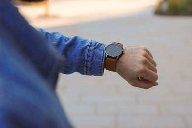 Photo of Man looking at watch outdoors, closeup. Being late concept