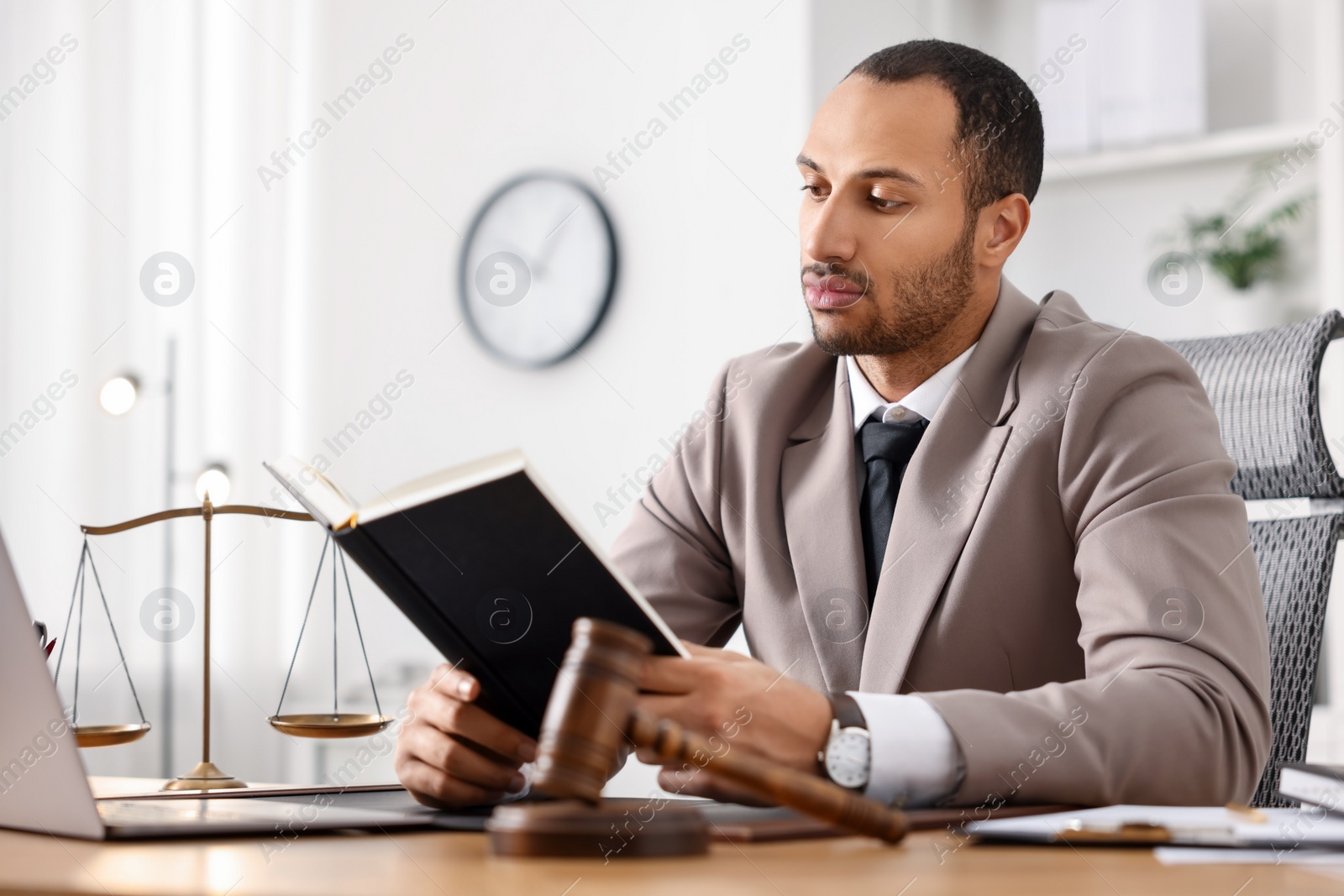 Photo of Serious lawyer reading book at table in office