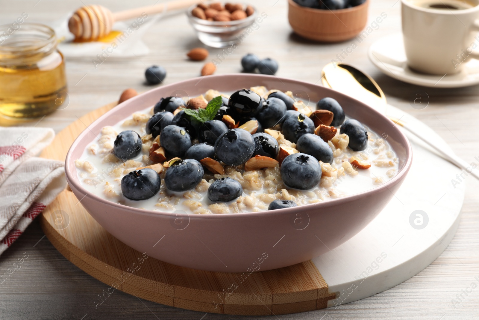 Photo of Tasty oatmeal porridge and ingredients served on wooden table. Healthy meal