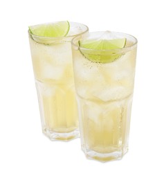 Photo of Glasses of tasty ginger ale with ice cubes and lime slices isolated on white