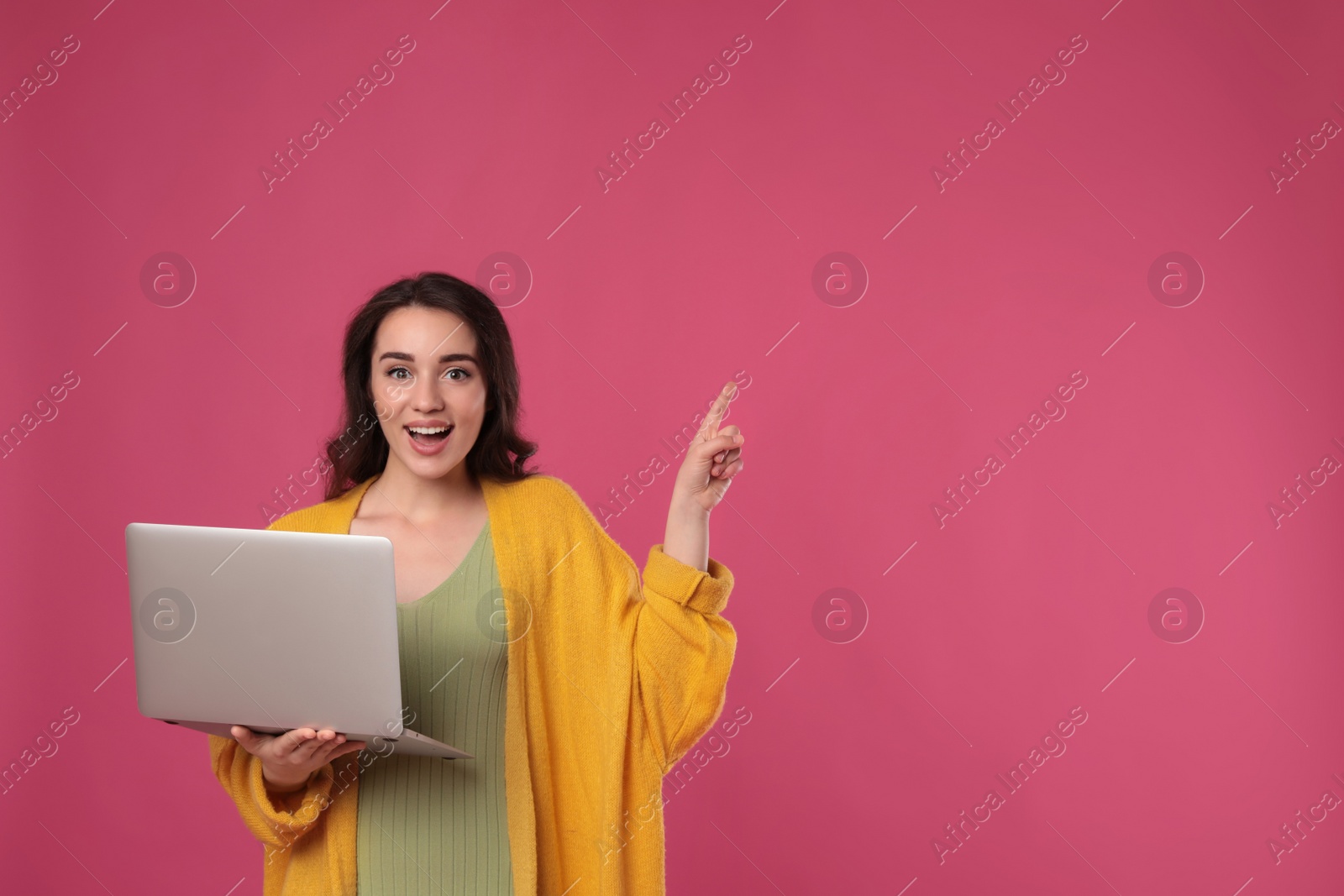 Photo of Young woman with laptop on pink background. Space for text