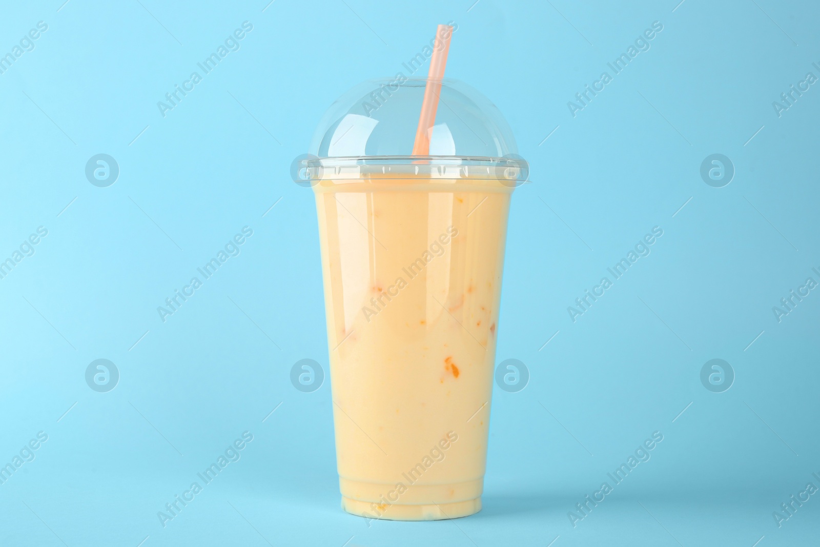 Photo of Plastic cup of tasty smoothie on light blue background