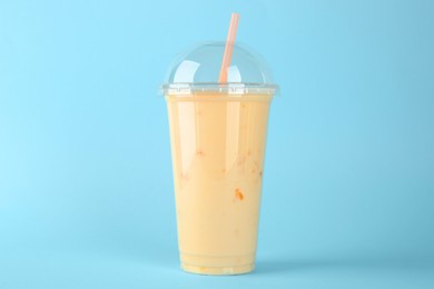 Plastic cup of tasty smoothie on light blue background