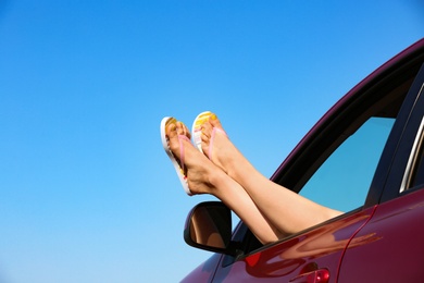 Photo of Closeup of woman showing legs with flip flops from car, space for text. Beach accessories