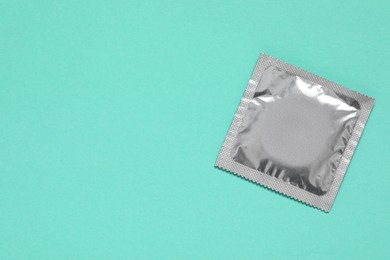Photo of Condom package on turquoise background, top view and space for text. Safe sex