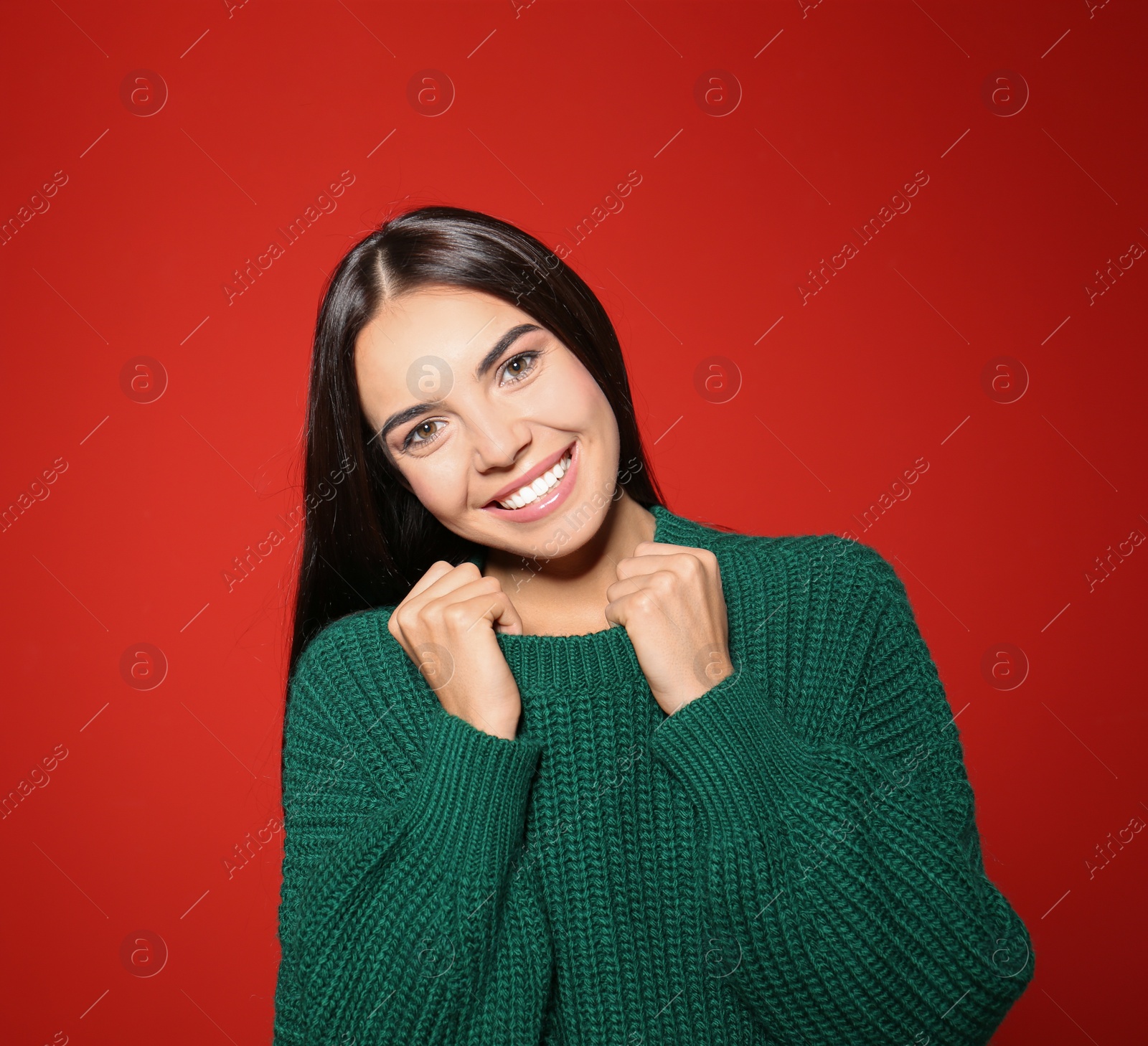 Image of Pretty woman wearing warm sweater on red background 