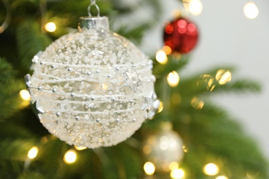 Photo of Beautiful holiday bauble hanging on Christmas tree, closeup. Space for text