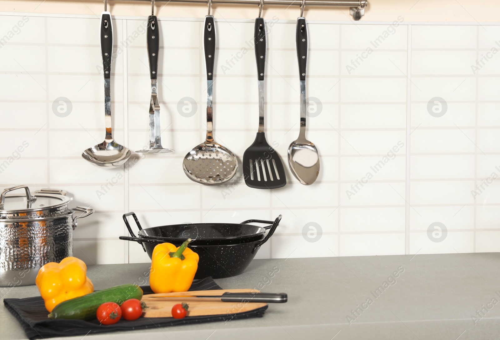 Photo of Set of clean cookware, utensils and products on table in modern kitchen. Space for text