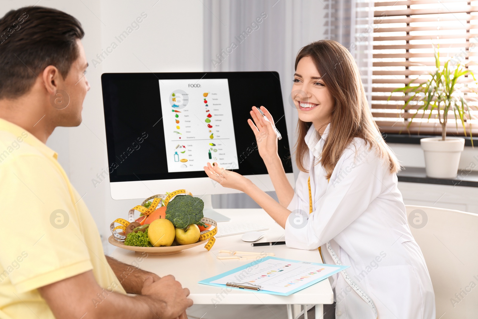 Photo of Young nutritionist consulting patient at table in clinic