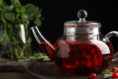 Photo of Tasty hot cranberry tea and fresh ingredients on wooden board