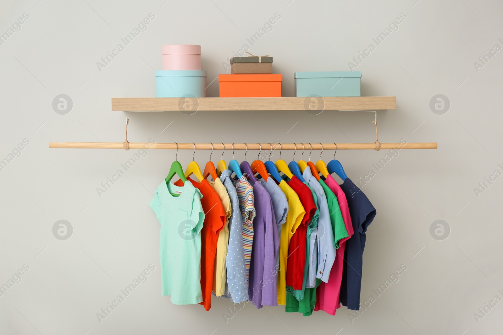 Photo of Rack with different clothes on light background