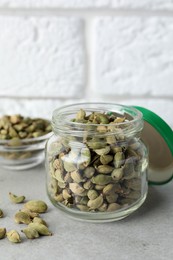 Photo of Jar with dry cardamom pods on light table