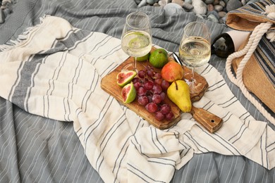 Photo of White wine and fresh fruits on picnic blanket outdoors