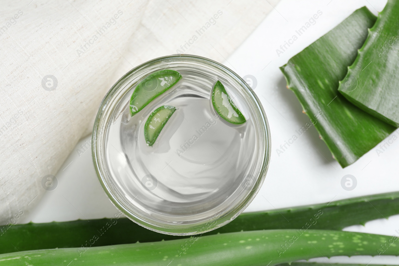 Photo of Fresh aloe juice in jar and leaves on white table, flat lay