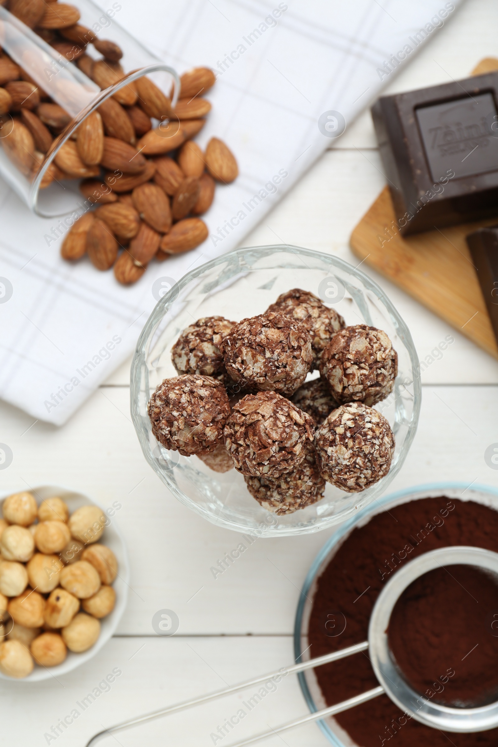 Photo of Tasty chocolate balls and ingredients on white wooden table, flat lay