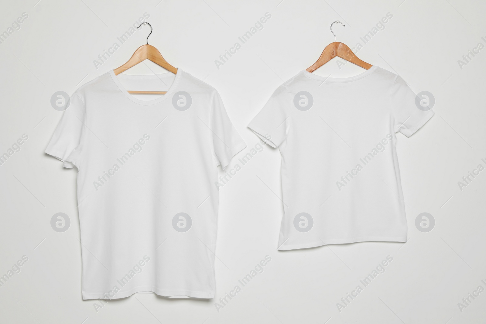 Photo of Hangers with blank t-shirts on white background. Mock up for design