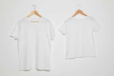 Hangers with blank t-shirts on white background. Mock up for design