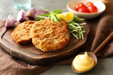 Photo of Tasty schnitzels served with sauce on grey table, closeup