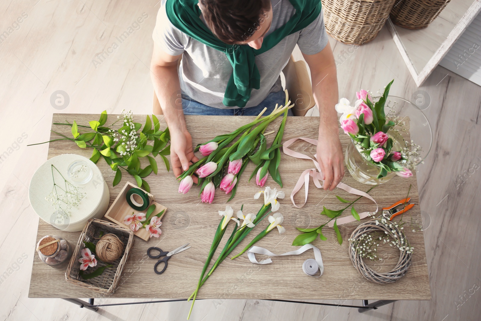 Photo of Male decorator creating beautiful bouquet at table, top view