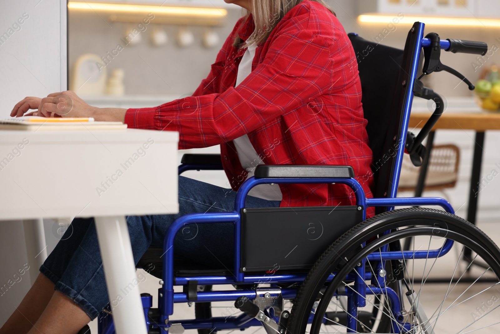 Photo of Woman in wheelchair at table indoors, closeup