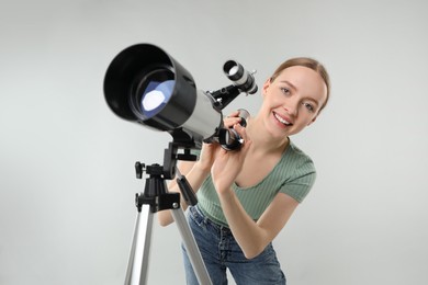 Young astronomer with telescope on grey background