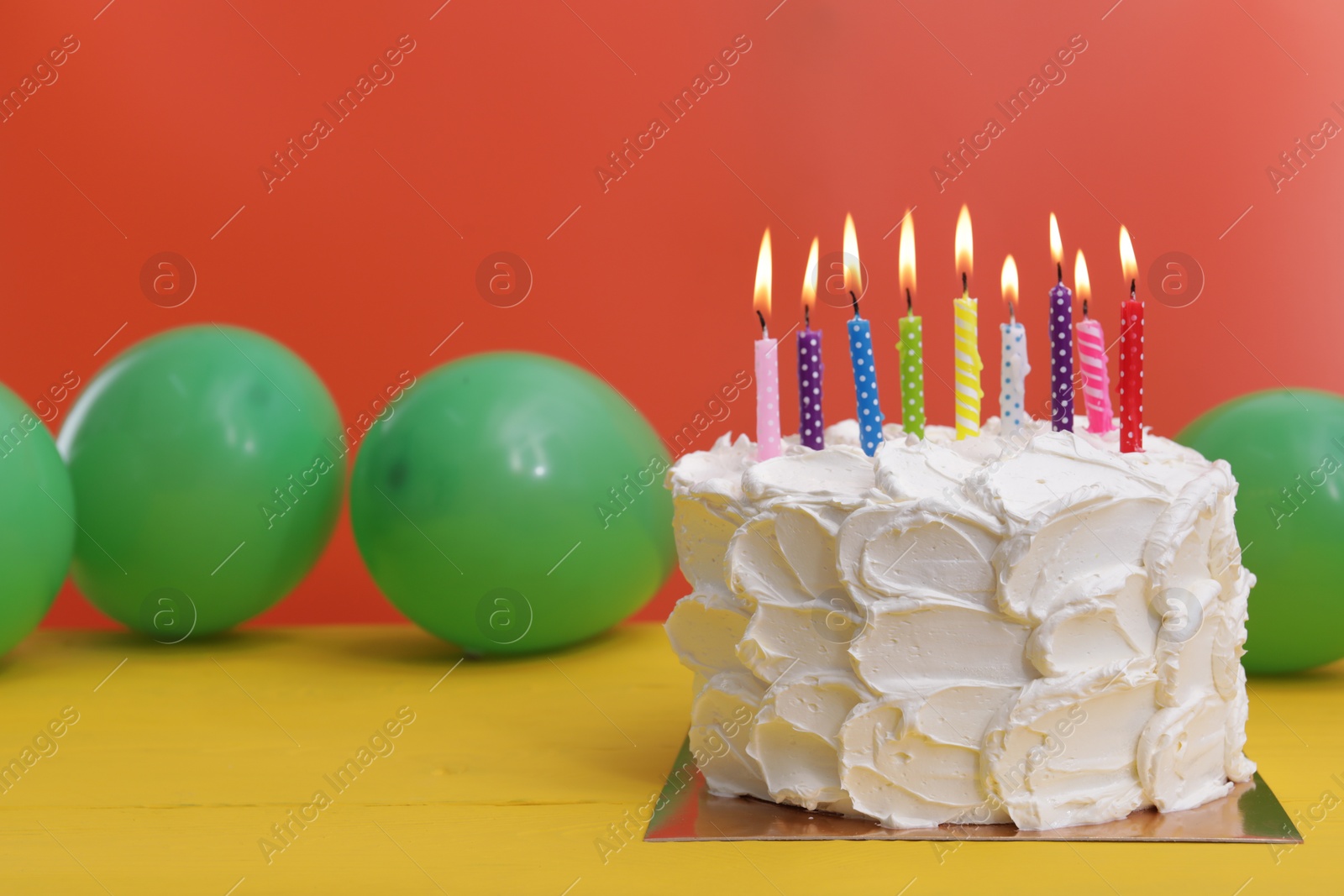 Photo of Delicious cake with burning candles and festive decor on yellow wooden table. Space for text