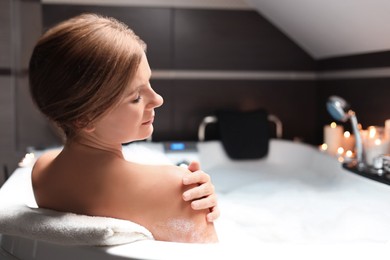 Beautiful woman taking bubble bath indoors. Romantic atmosphere