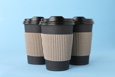Paper cups with black lids on light blue background. Coffee to go