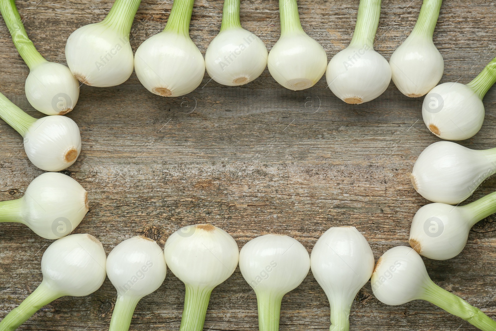 Photo of Frame made of green spring onions on wooden table, flat lay. Space for text