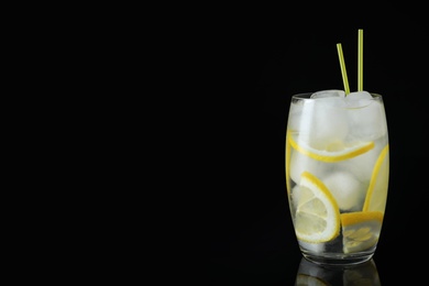 Photo of Glass of cocktail with vodka, ice and lemon on black background. Space for text