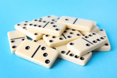 Photo of White domino tiles on turquoise background, closeup
